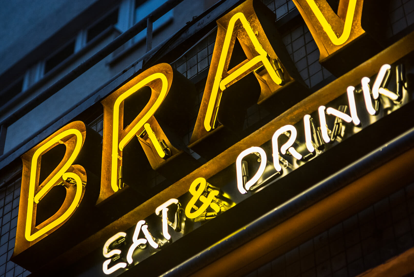 neon-bravo-eat-drink-neon-nad-wejsciem-do-restauracji-neon-na-kaflach-neon-na-scianie-z-kafli-neon-podswietlany-neon-wewnatrz-blachy-nierdzewnej-neon-na-zewnatrz-zolty-neon-warszawa-centralna